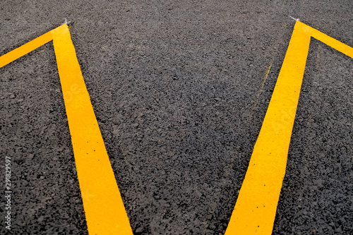 Band of yellow reflective paint on a black asphalt surface, an abstract perspective of road markings.