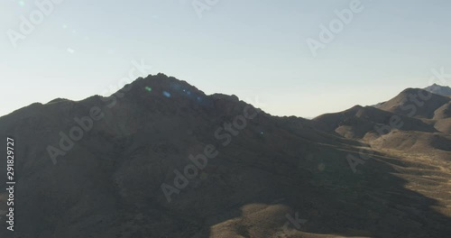 Aerial shot, day, spin to side view of mountains casting shadow underfoot, drone