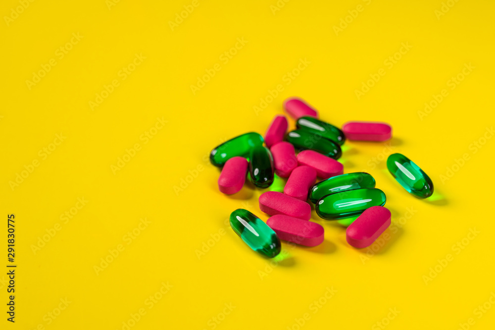A small number of tablets and capsules on a yellow background.The concept of pharmacology. A small number of tablets and capsules on a yellow background.The concept of pharmacology.