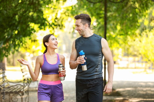 Sporty young couple with bottles of water in park