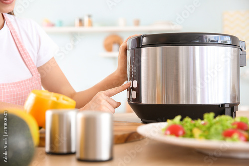 Fotografie Woman using modern multi cooker in kitchen