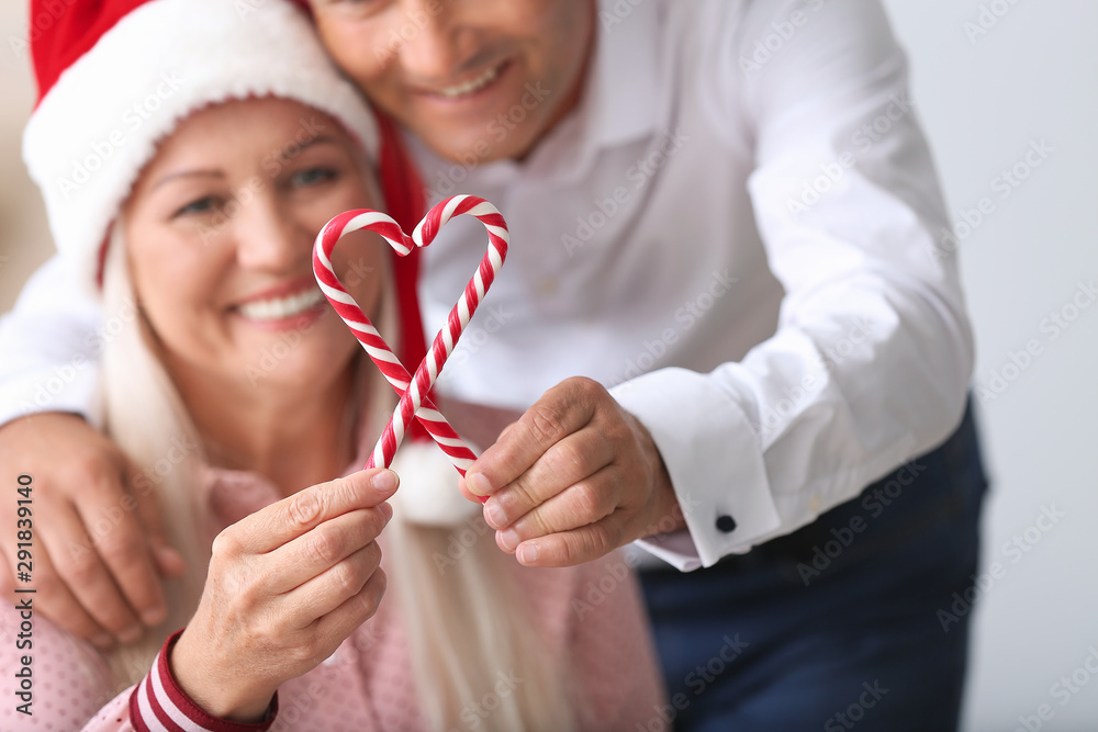 Happy mature couple with Christmas candy canes at home Happy mature couple with Christmas candy canes at home