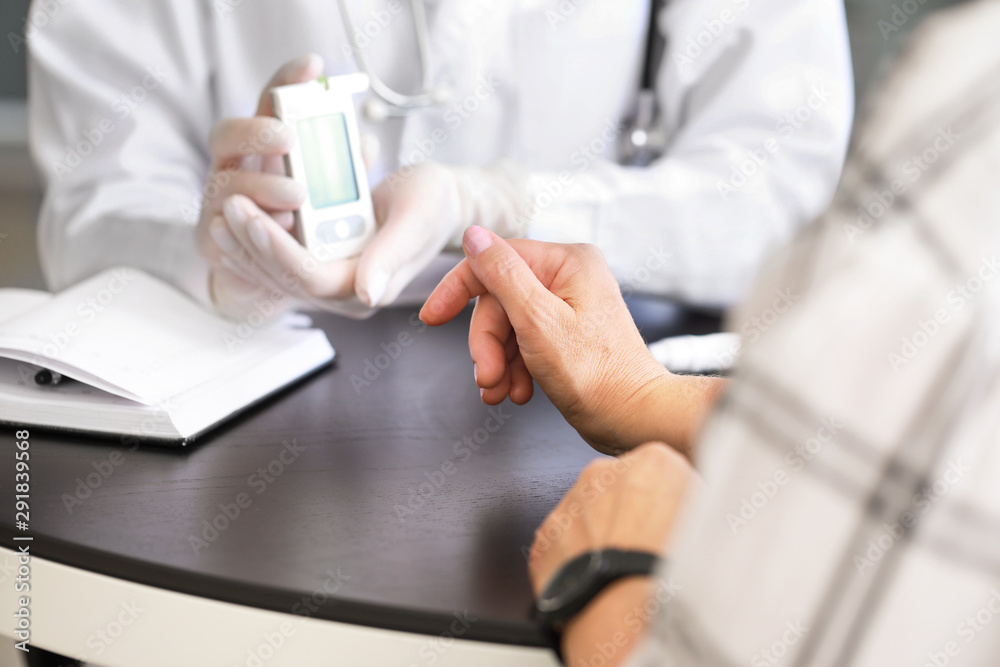 Doctor checking blood sugar level of diabetic patient in clinic Doctor checking blood sugar level of diabetic patient in clinic