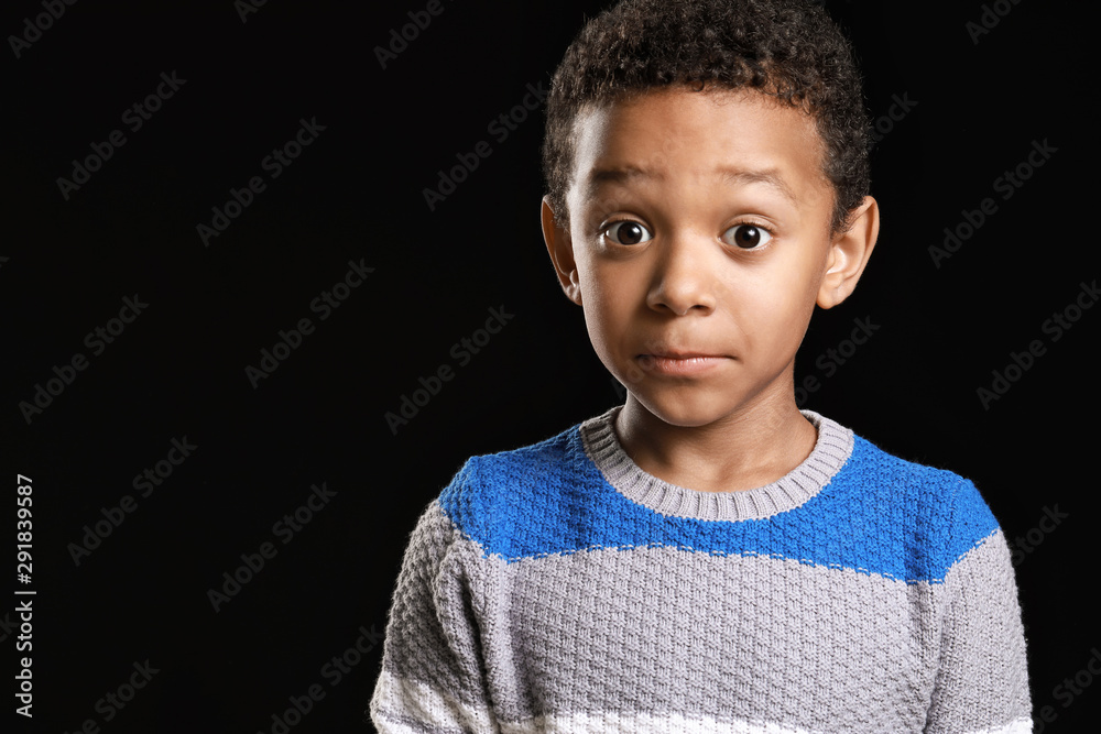 Surprised African-American boy on dark background Surprised African-American boy on dark background