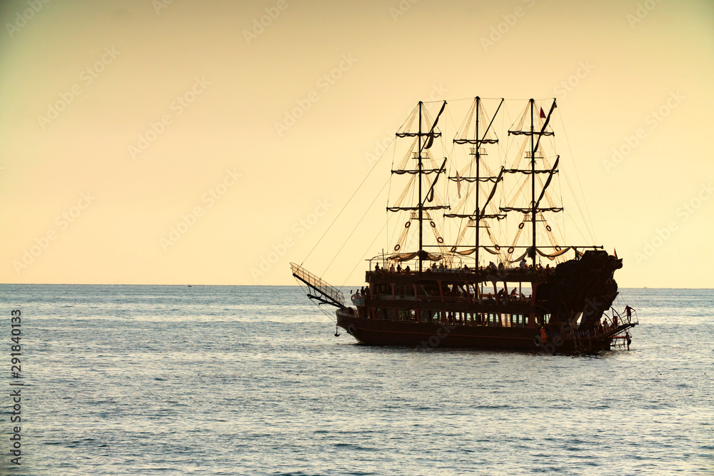 Obraz premium old pirate ship sailing at sea sunset