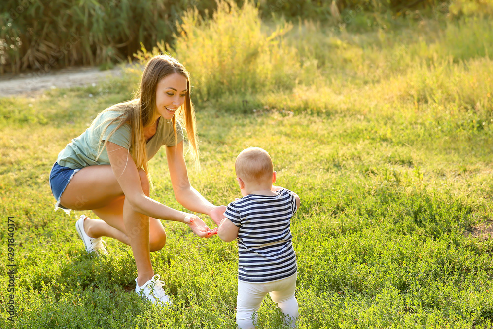 Fototapeta premium Mother teaching her little baby to walk outdoors