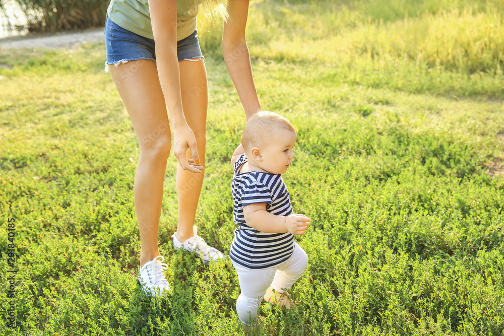 Mother teaching her little baby to walk outdoors Mother teaching her little baby to walk outdoors
