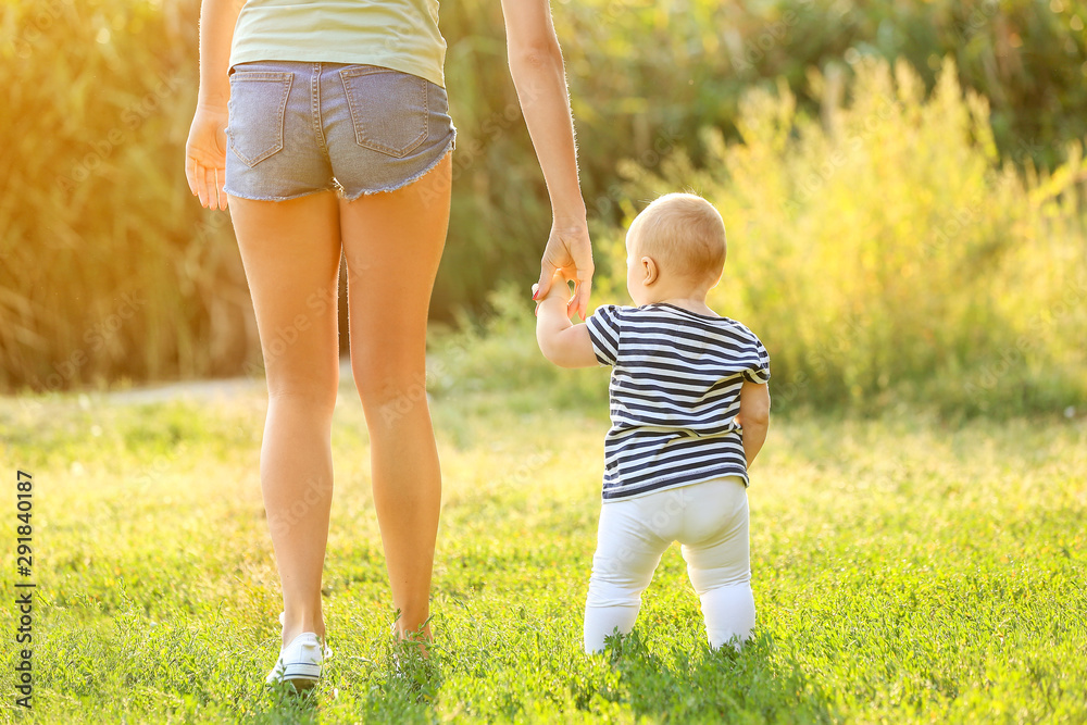 Fototapeta premium Mother teaching her little baby to walk outdoors