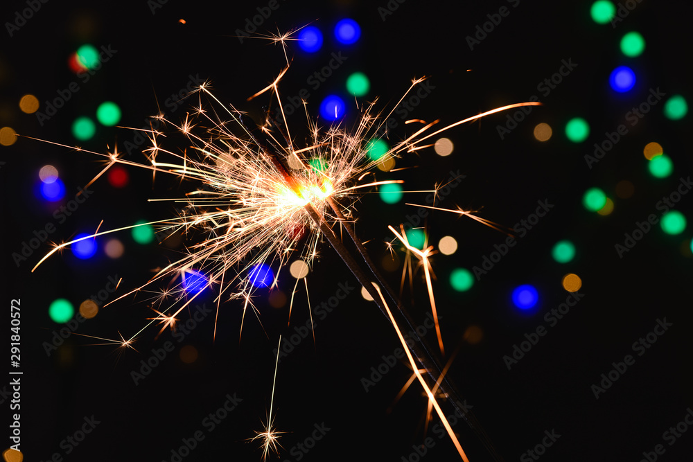 Obraz premium Christmas sparklers on dark background with defocused lights