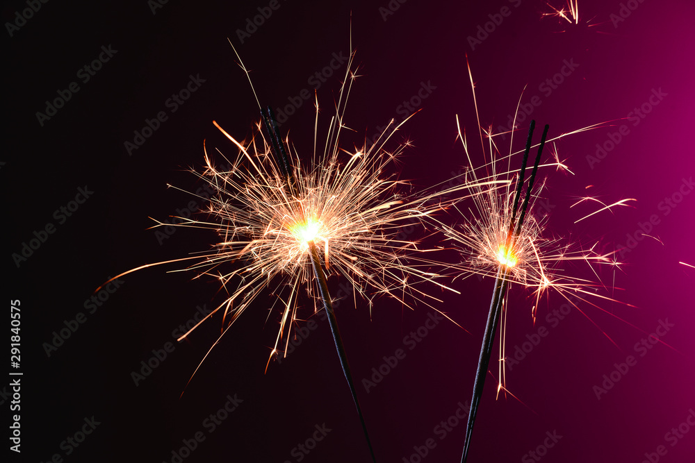 Christmas sparklers on color background