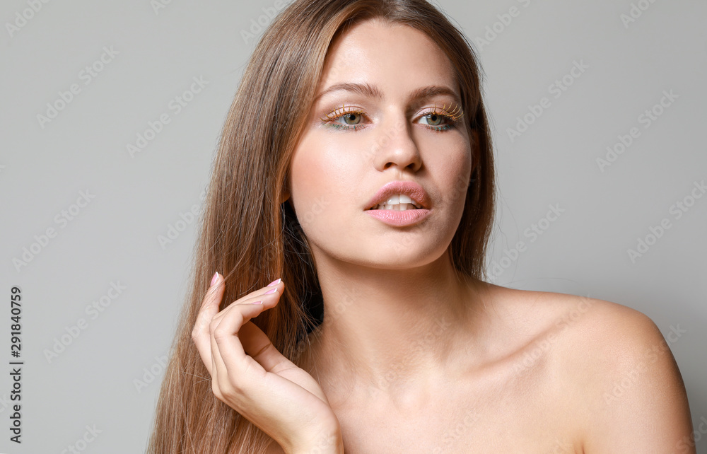 Young woman with creative eyelashes on grey background