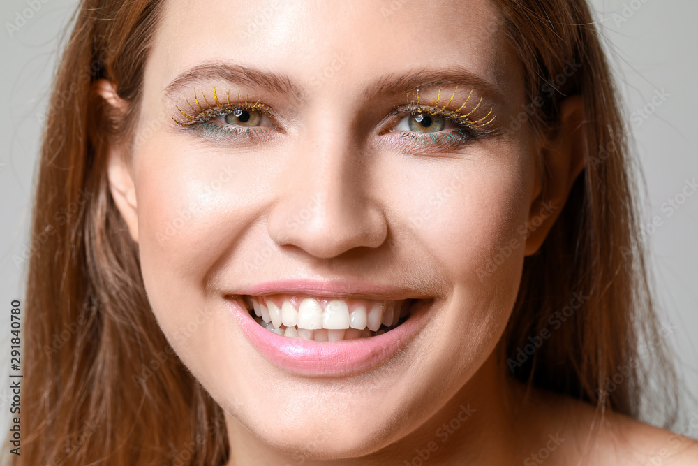 Young woman with creative eyelashes on grey background, closeup Young woman with creative eyelashes on grey background, closeup