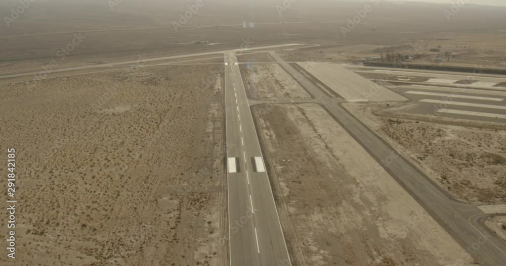 Aerial shot, day, view runway and pan to military hangar in desert, drone Aerial shot, day, view runway and pan to military hangar in desert, drone