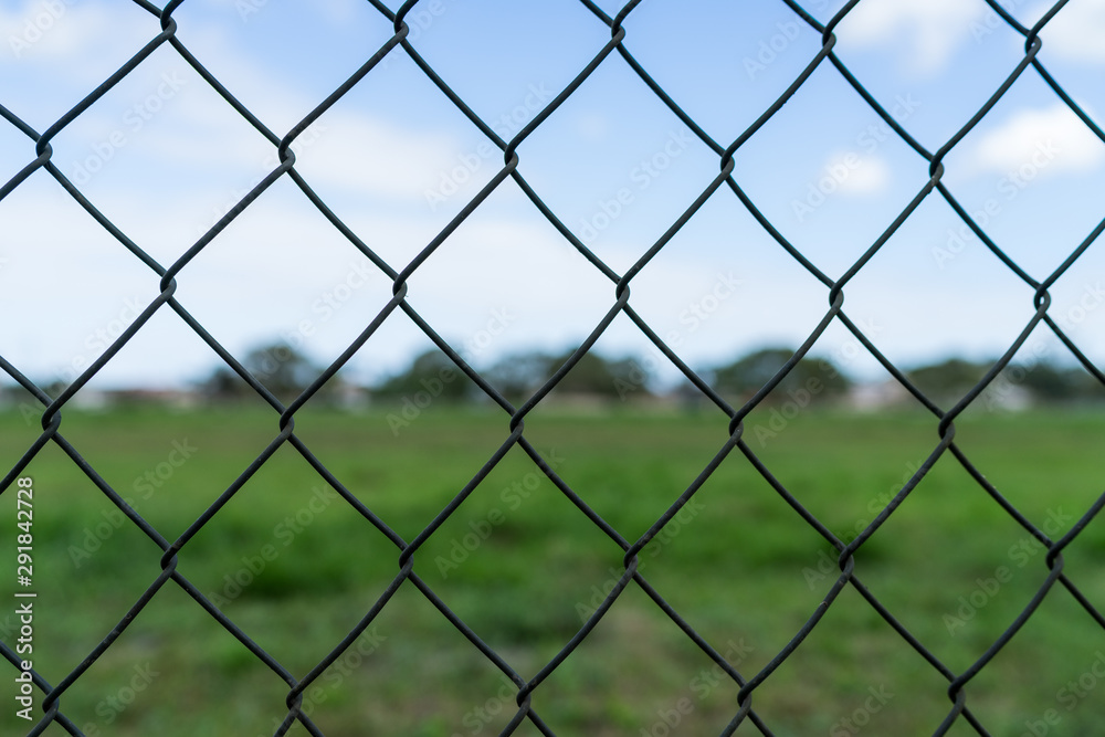 Wire fence with blue sky and green glass in bokeh on the background Wire fence with blue sky and green glass in bokeh on the background