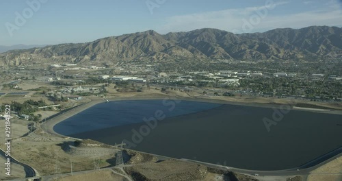 Helicopter aerial shot of body of water, highway and mountains, drone