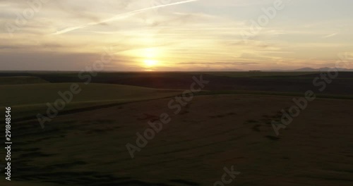 Hazy yellow sunset over green hills, drone, helicopter aerial 