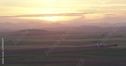 Hazy sunset over green fields, helicopter aerial shot, drone