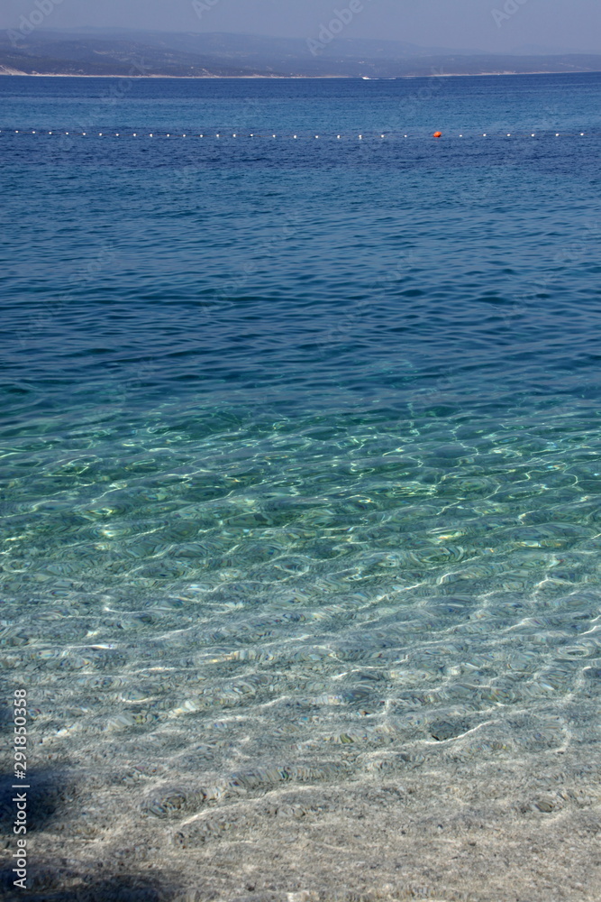 Surface of sea by the gravel beach with line of swimming area
