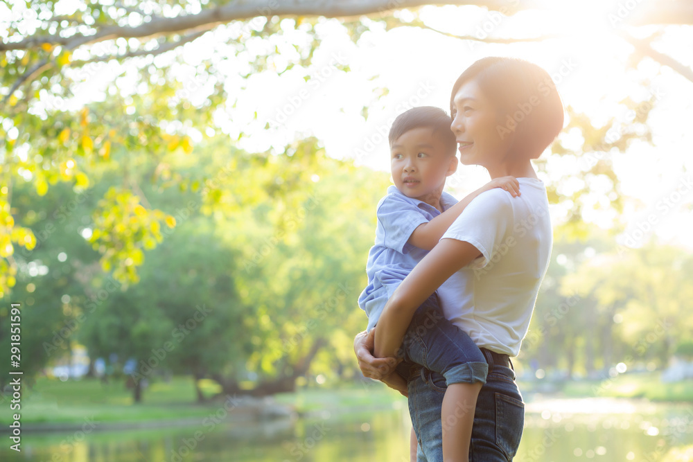 Beautiful young asian mother carrying little boy in the park, asia woman happy having son and hug kid, mom love and embracing child together in summer, mother day and family concept. - obrazy, fototapety, plakaty 