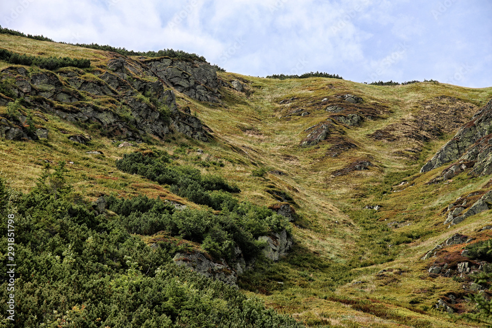 Steep mountain hillside with grass and rocks Steep mountain hillside with grass and rocks