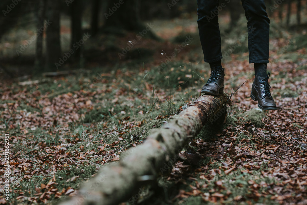 Crop man in black boots walking on trunk Crop man in black boots walking on trunk