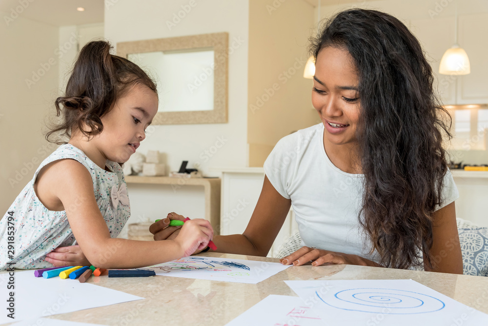 Litlle girl drawing with her mom with color waxes at home Litlle girl drawing with her mom with color waxes at home