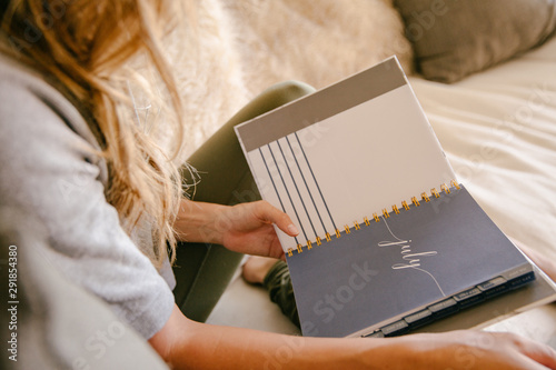 A young woman filling our her planner at home.
