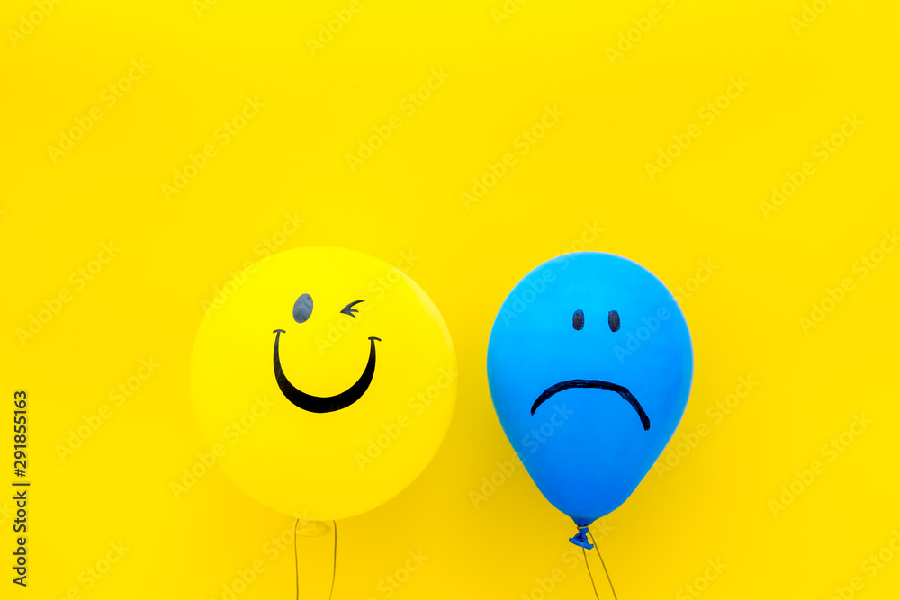 Treat depression concept. Balloons with sad and smiling faces on yellow background top view space for text