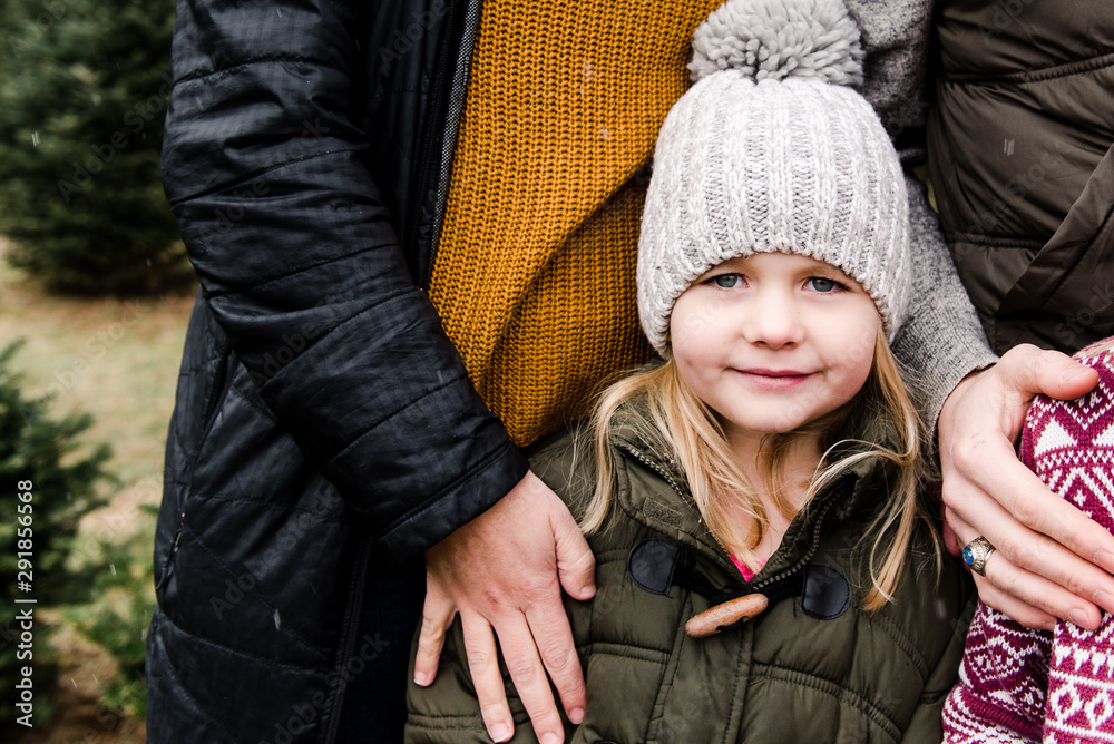 portrait little girl in big woolly hat in Christmas tree farm portrait little girl in big woolly hat in Christmas tree farm