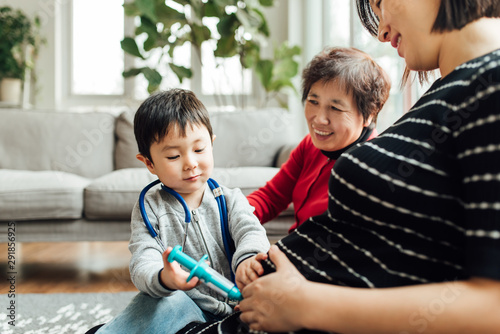 Cute boy examining pregnant mother with a stethoscope and a shot photo