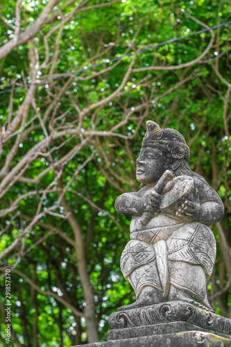 A statue of man wearing a  traditional Bali s clothes  playing a music