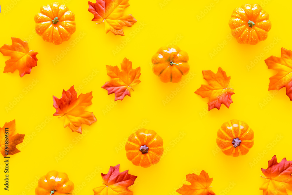 Autumn composition. Pattern with red and orange leaves and pumpkins on yellow background top view