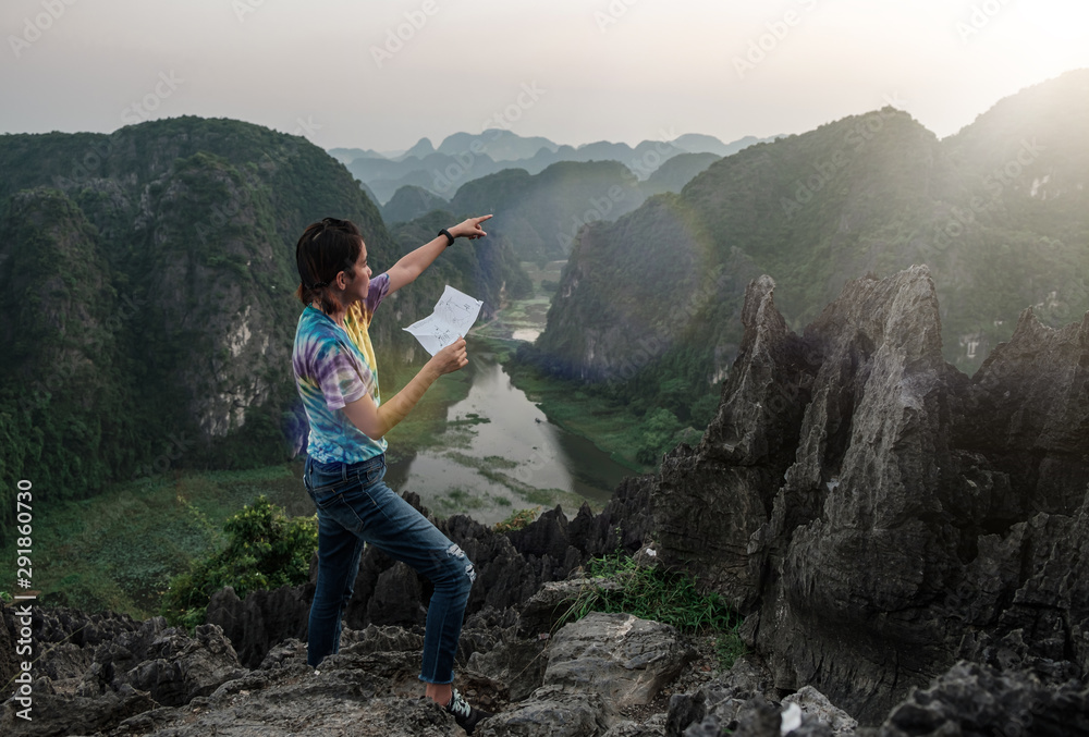 Obraz premium young travelers point to travel through a map in hand. On a scenic hilltop along the way. at Hang Mua, Ninh Bình in Vietnam.