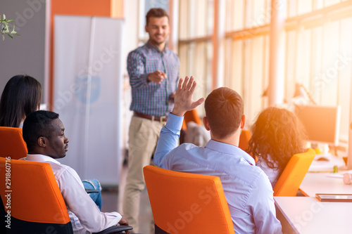 Young colleagues raising hands at the business meeting in office