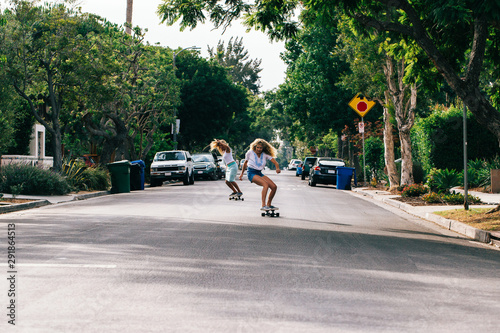 Two Young California Girls Skateboarding Sunny Streets of Venice