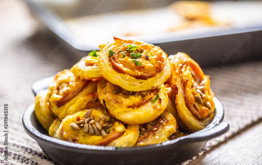 Rolls of puff pastry with ham bacon cheese sesame in dish Rolls of puff pastry with ham bacon cheese sesame in dish
