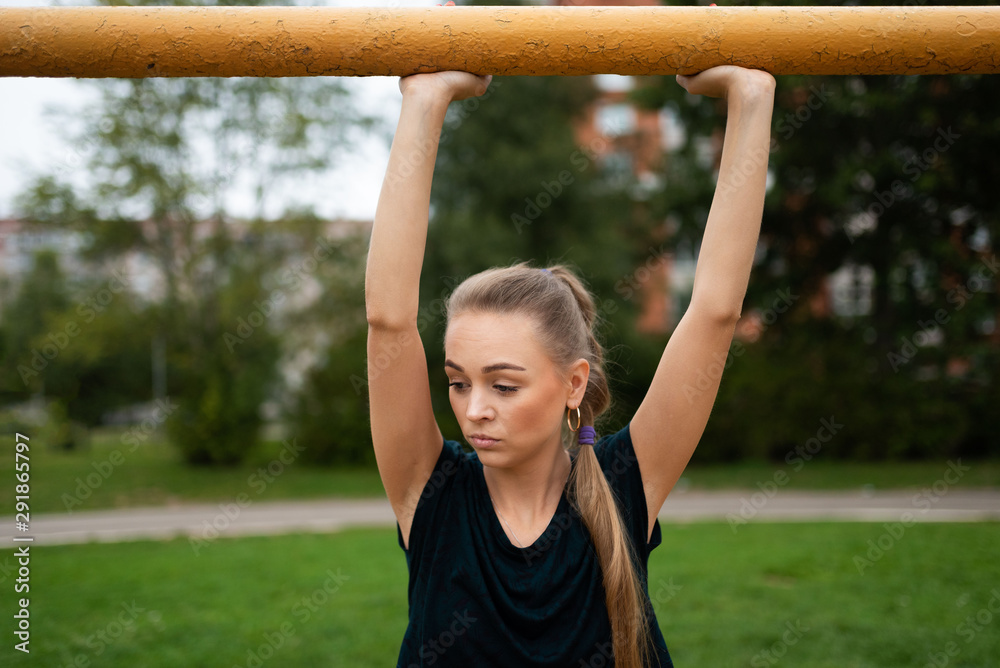 Fototapeta premium Athletic blonde girl holds hands on the crossbar of a football goal.