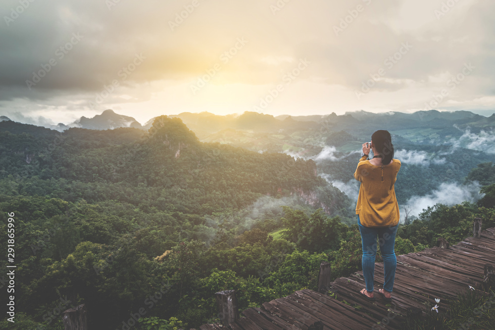Woman traveler take a photo of sunrise with beautiful moutain scenes in Ban Cha Bo, Mhong Mountaineer village the north of Thailand, Inspiration concept