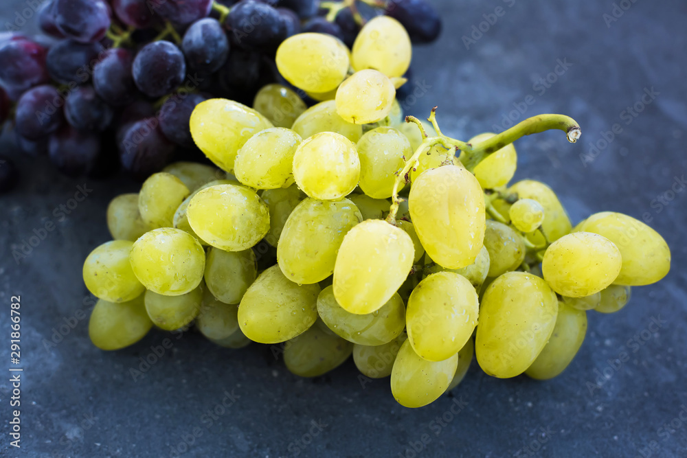 Bunches of ripe green and blue grapes close-up on a blue shabby concrete background Bunches of ripe green and blue grapes close-up on a blue shabby concrete background
