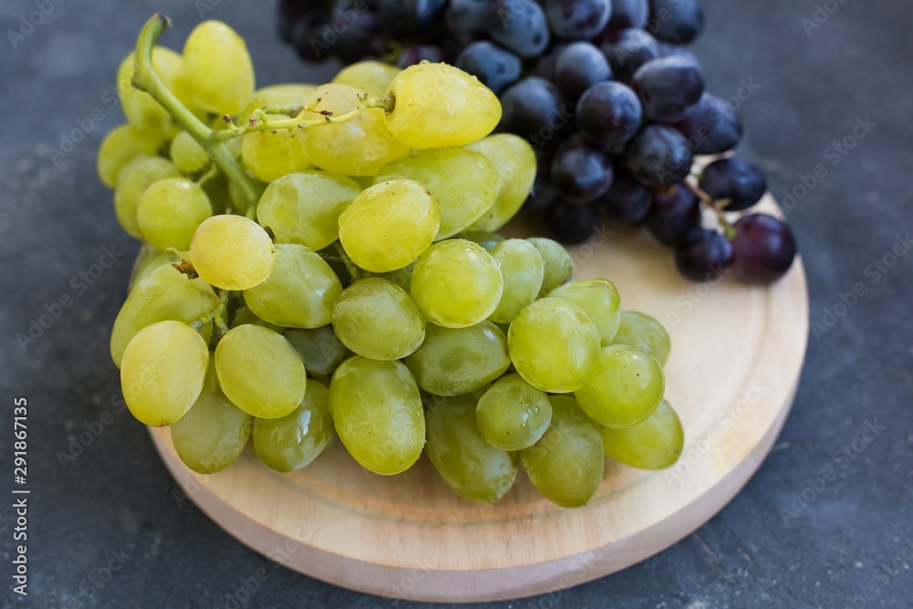 Bunches of ripe green and blue grapes close-up on a blue shabby concrete background Bunches of ripe green and blue grapes close-up on a blue shabby concrete background