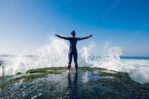 Woman feel free and strong at the seaside cliff edge facing the coming strong sea waves