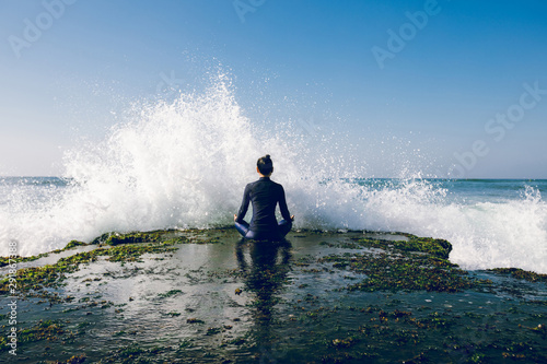 Yoga woman meditation at the seaside cliff edge facing the coming strong sea waves © lzf