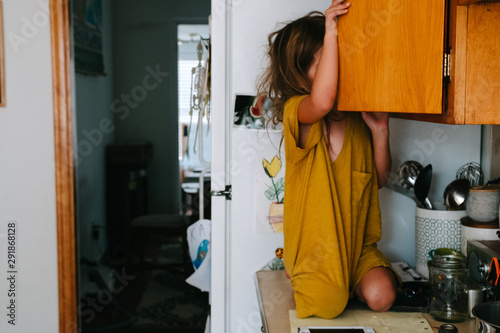 child on counter looking in cupboard photo