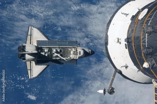 Fototapeta Naklejka Na Ścianę i Meble -  Space shuttle flies under the space station. Elements of this image were furnished by NASA