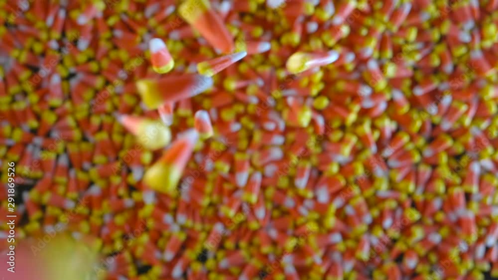 Pieces of candy corn are seen slowly dropping into a large pile of candy corn.