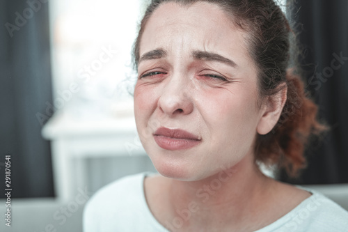 Mature woman with facial wrinkles crying having allergy