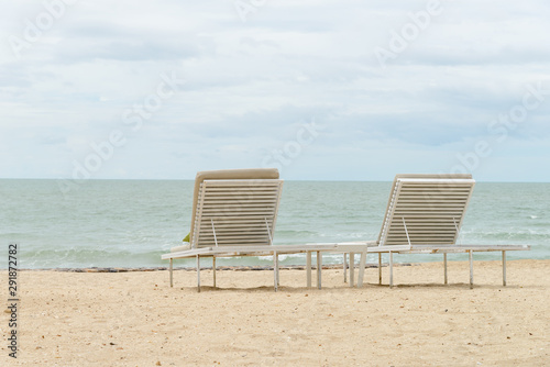 empty two beach chairs on a beautiful beach at sunny day - vacation in summer time