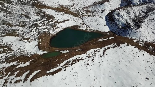 Mountain lake among the snowy peaks. Lake at an altitude of 3377 m. Beautiful panorama of snowy mountains, white clouds, green water of the lake. Flying in the mountains on a drone. Almaty, Kazakhstan photo