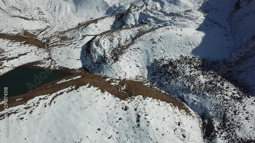 Mountain lake among the snowy peaks. Lake at an altitude of 3377 m. Beautiful panorama of snowy mountains, white clouds, green water of the lake. Flying in the mountains on a drone. Almaty, Kazakhstan photo