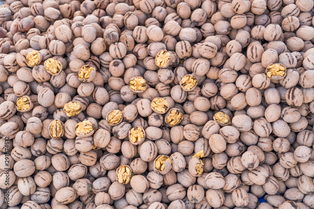 Walnuts, some of them crushed,  stacked on a surface as background.